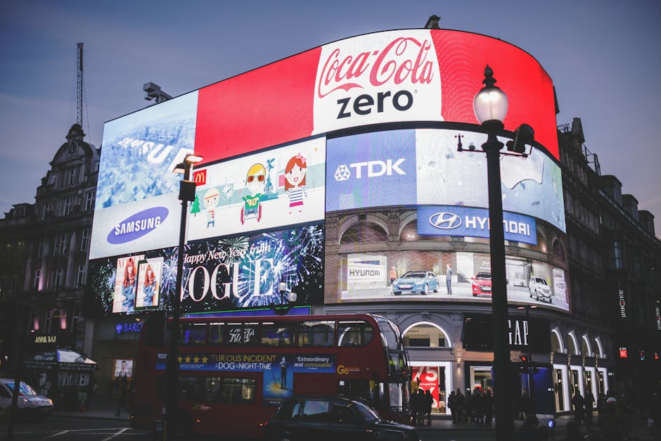 Night view of Piccadilly Circus in London with bright billboards and a red double-decker bus.